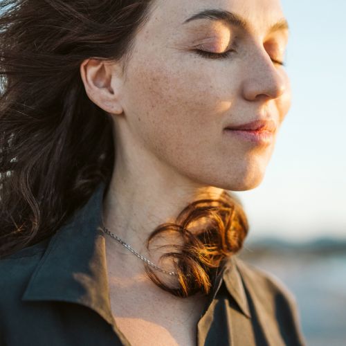 Portrait of a calm woman with hair flying in the wind on the beach.